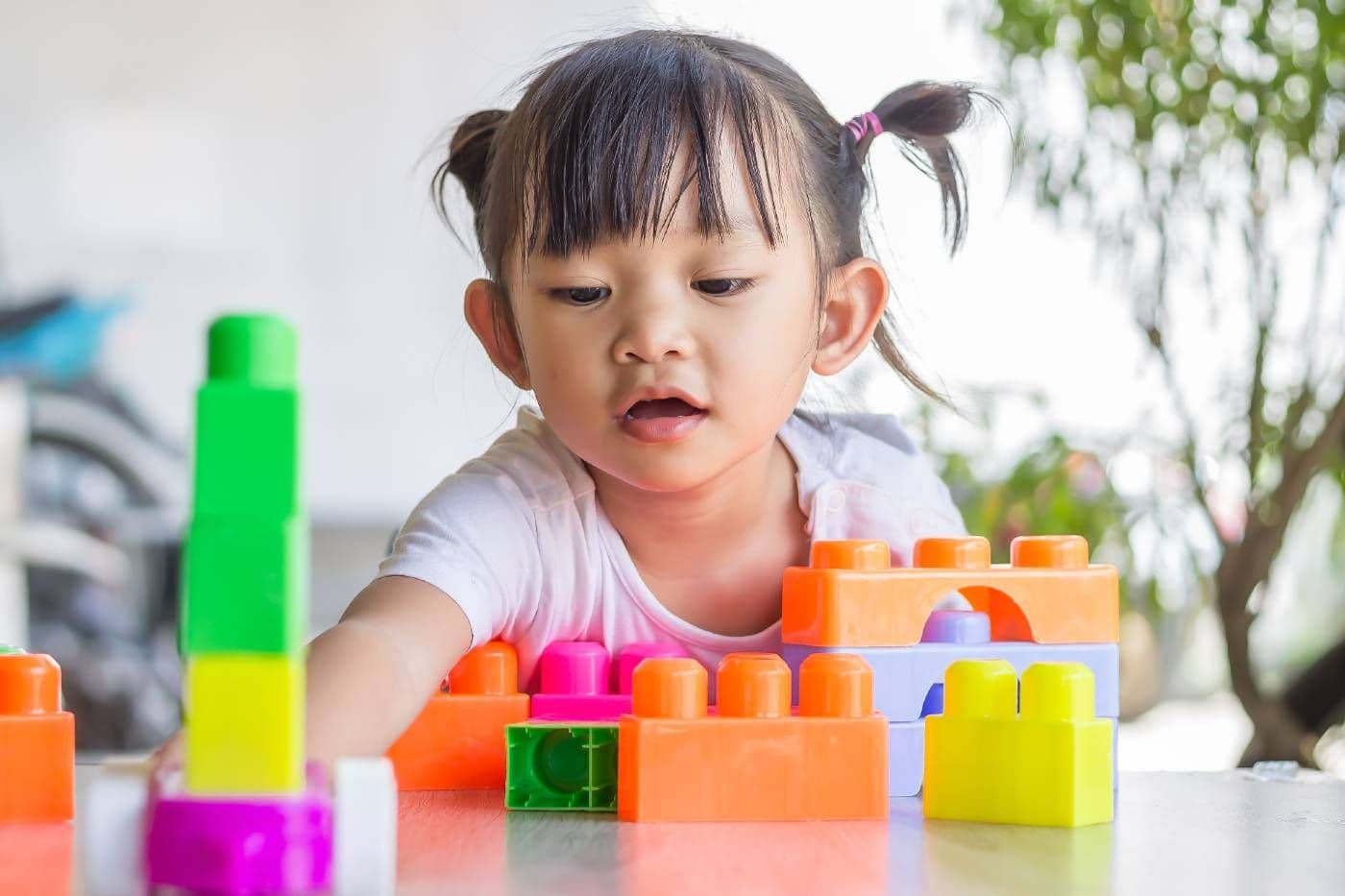 Toddler girl plays with colorful blocks
