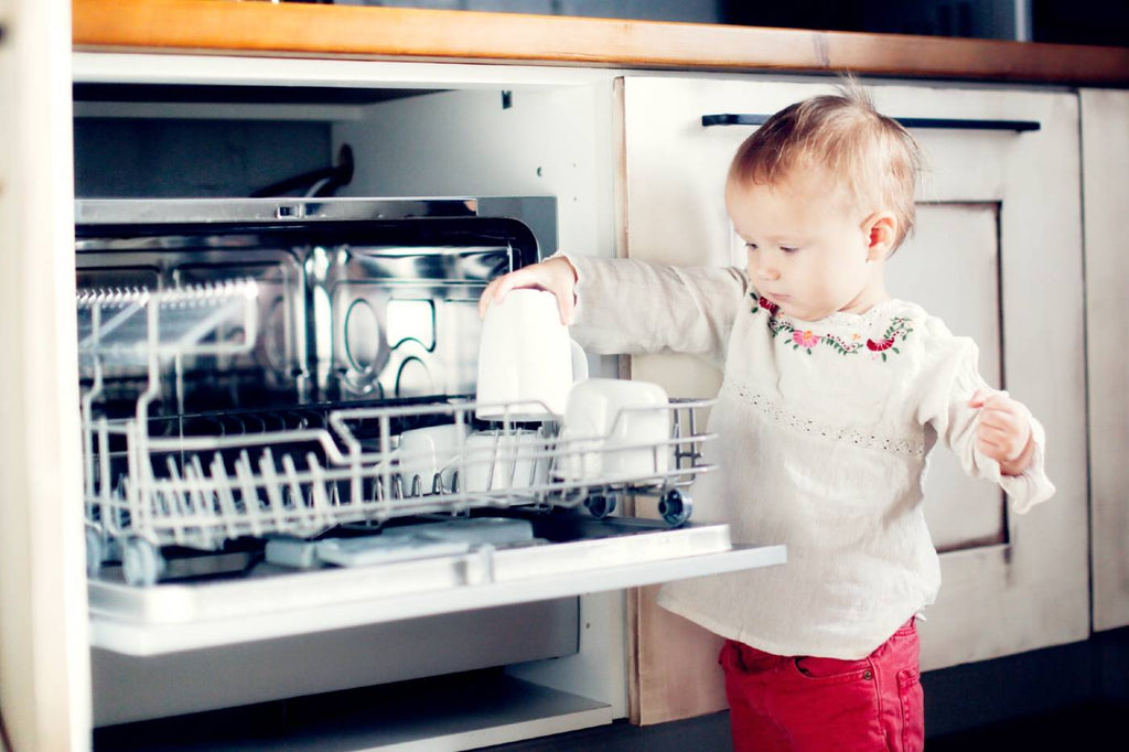 Dish washing concept. Child boy washing the dishes in the kitchen